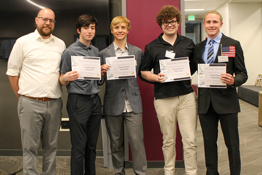 Five men proudly display certificates in a modern office setting, smiling and standing together.